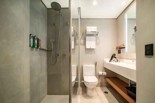 uma casa de banho com um chuveiro, um WC e um lavatório. em Grand Mercure SP Itaim Bibi em São Paulo