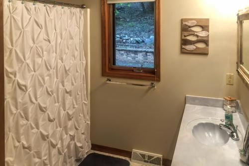 a bathroom with a white shower curtain and a sink at Lakefront Hideaway in Eureka Springs