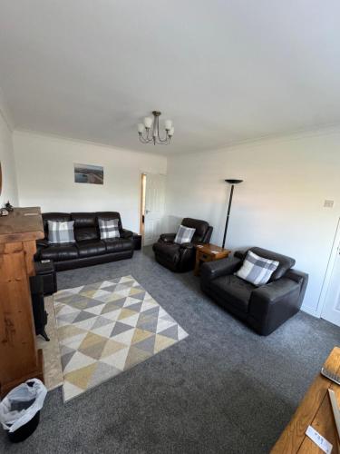 a living room with two black couches and a rug at Four mile bridge by Trearddur bay in Valley