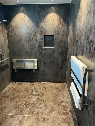 a bathroom with a tiled floor and a tv on the wall at Plume Villas in Matakana