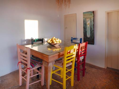 a dining room with a wooden table with colorful chairs at Annas Katikia in Drymonas