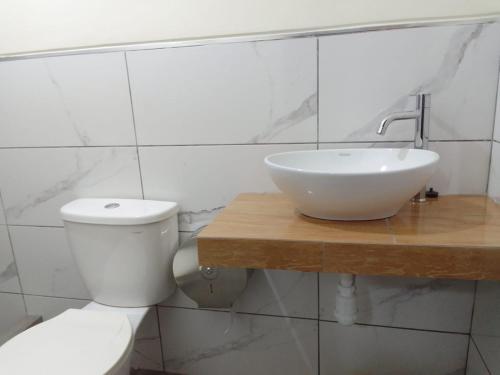 a white bathroom with a sink and a toilet at Gran Imperial Avenida in Tumbes