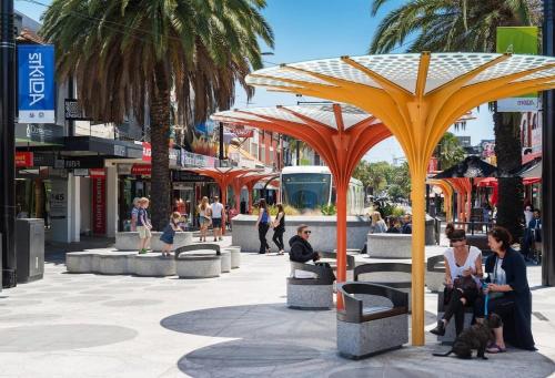 a group of people sitting on benches in a street at 1 Bdrm With Parking, Walk to Beach in Melbourne
