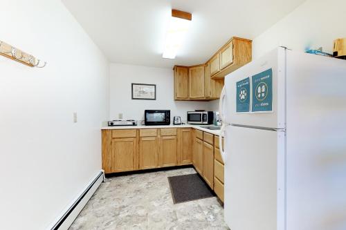 a kitchen with wooden cabinets and a white refrigerator at Three Sisters Peak Cabin at Filoha Meadows in Redstone