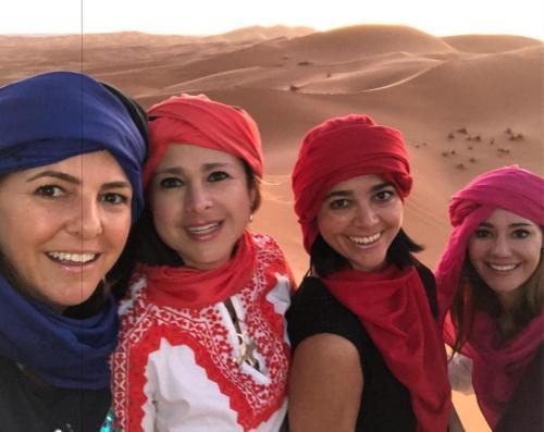 three women wearing turbans standing in front of a desert at Holiday Desert Camp in Merzouga