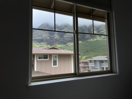a window with a view of a house at New 4 Bedroom Home with Ocean and Gorgeous Mountain Views in the gated community of Mauna Olu in Waianae