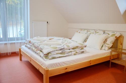 a bedroom with a wooden bed with white sheets and pillows at Mezi Stromy in Brno
