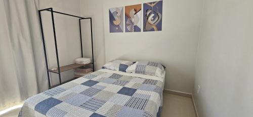 Schlafzimmer mit einem Bett mit einer blauen und weißen Bettdecke in der Unterkunft Casa Duplex Esperança - Ar e Garagem Privativa in Bom Jesus da Lapa