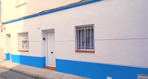 een wit en blauw gebouw met een deur bij Can Trafalgar - Casita en pueblo marinero in L'Ametlla de Mar