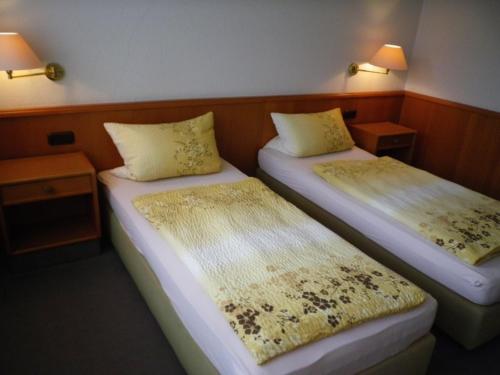 Stadthotel Oldenburg في أولدنبورغ: سريرين في غرفة صغيرة بها مصباحين
