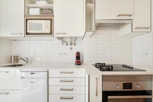 a white kitchen with white cabinets and a stove at Sunny - Cozy Apartment in Amadora