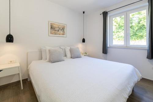 - une chambre blanche avec un lit blanc et une fenêtre dans l'établissement Apartments with a parking space Hvar - 22023, à Hvar