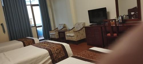 um quarto de hotel com três camas e uma televisão em Ngọc Lan Hotel em Ho Chi Minh