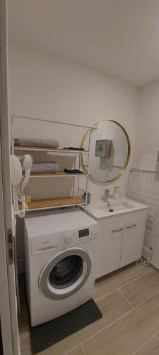 - un lave-linge dans la salle de bains pourvue d'un miroir dans l'établissement Appartement cosy, à Saint-Nazaire