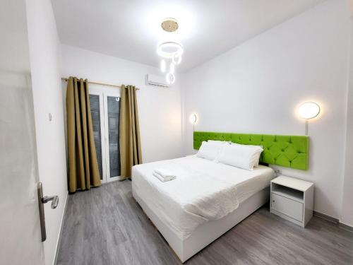 a bedroom with a white bed and a green headboard at AHAMED GREEK SMPCO in Athens