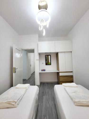 a white room with two beds and a chandelier at AHAMED GREEK SMPCO in Athens