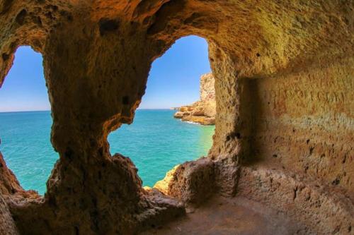 a view of the ocean through a rock formation at Casa Pios in Carvoeiro