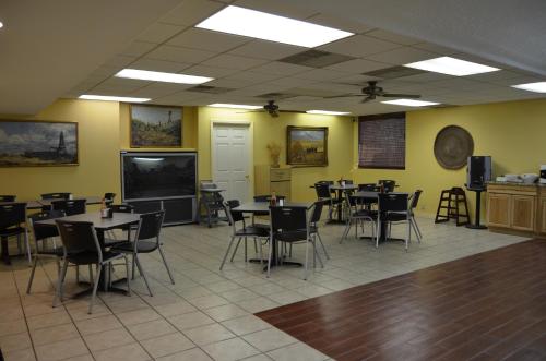 a dining room with tables and chairs and a flat screen tv at Plaza Inn in Big Spring