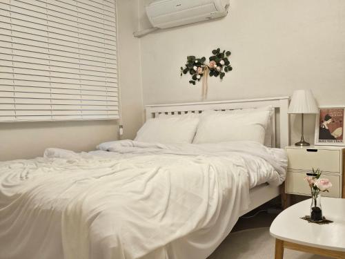 biała sypialnia z białym łóżkiem z białą pościelą w obiekcie Liebe House w Seulu