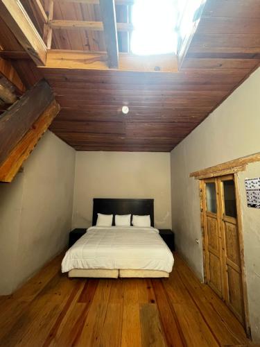 uma cama num quarto com pisos e tectos em madeira em The Coffee Bean Hostel em San Cristóbal de Las Casas