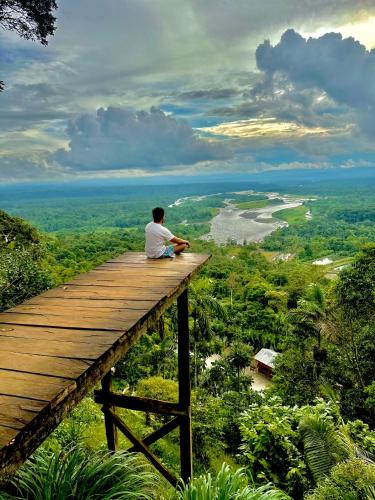 a man sitting on top of a wooden walkway at Amazon Puyu Glamping in Tarqui