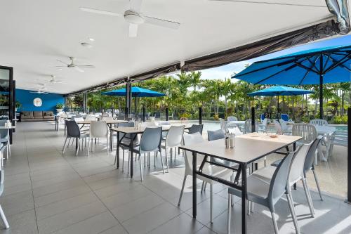 um restaurante com mesas, cadeiras e guarda-sóis azuis em Quality Resort Parkhurst em Rockhampton