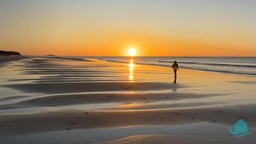 a person walking on the beach at sunset at Wave Song - minutes to the shore in Caves Beach
