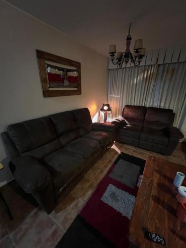 a living room with a leather couch and a table at Departamento Pucon in Pucón
