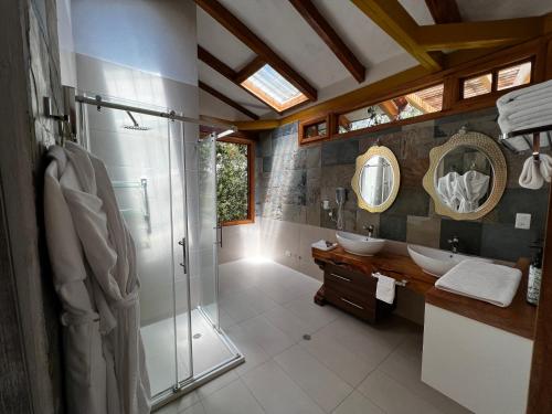 un bagno con due lavandini e una doccia in vetro di Hacienda Jimenita Wildlife Reserve a Puembo