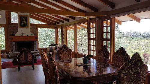 a dining room with a wooden table and some windows at Hacienda Jimenita Wildlife Reserve in Puembo