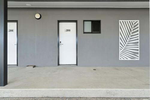 a white building with three doors and a clock at Quality Resort Parkhurst in Rockhampton