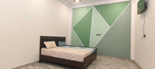AyodhyaにあるHotel O Pranav Innの緑の壁の客室の小さなベッド1台分です。