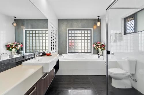 a bathroom with two sinks and a tub and a toilet at Quality Resort Parkhurst in Rockhampton