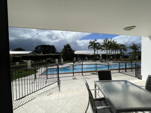 a patio with a table and chairs next to a swimming pool at The Boathouse Resort Luxury Apartments in Tea Gardens