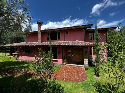 a red house with a brick path in front of it at Hacienda Jimenita Wildlife Reserve in Puembo