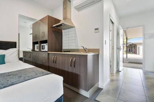 a bedroom with a bed and a kitchen with a sink at Quality Resort Parkhurst in Rockhampton