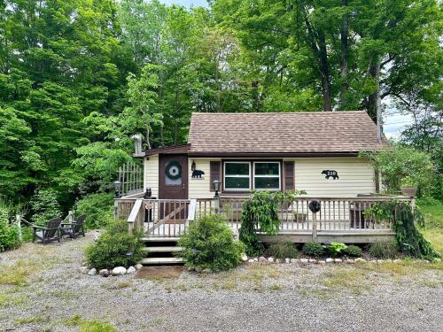 a small house with a porch in a yard at Escape to a Streamside Cabin in the Lower Catskills in Wurtsboro