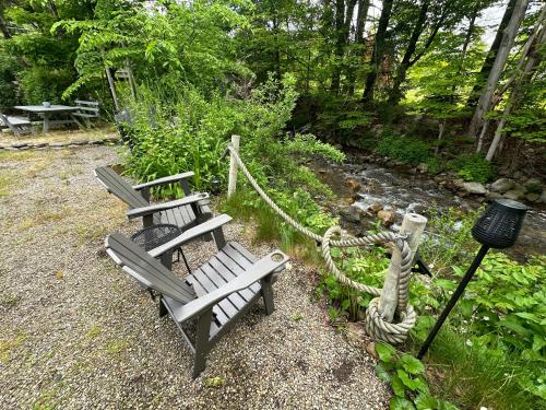 two wooden benches sitting in front of a stream at Escape to a Streamside Cabin in the Lower Catskills in Wurtsboro