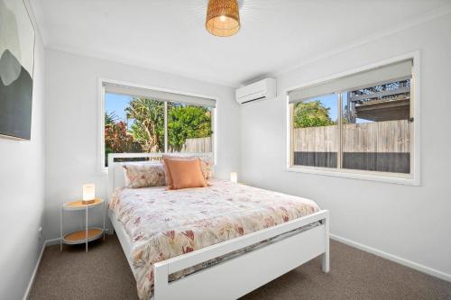 a white bedroom with a bed and a window at Marcoola Surfside Escape in Marcoola