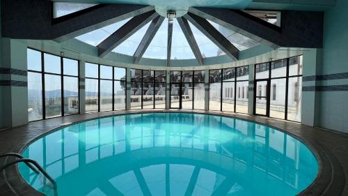 a large swimming pool in a building with windows at Apartamento no Home Green Home - Vista para a montanha in Campos do Jordão