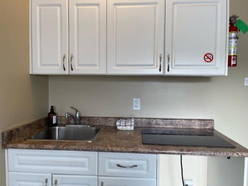 encimera de cocina con fregadero y armarios blancos en Diplomat Motel en Nanaimo