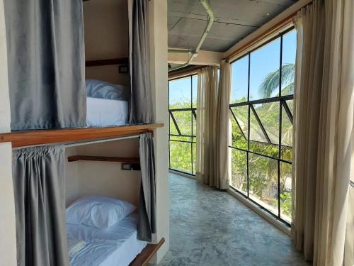 a room with two bunk beds and large windows at Elmar hostal in Bacalar