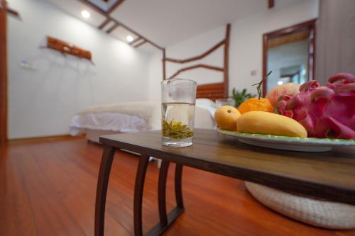a bowl of fruit on a table with a glass at Easy House in Zhangjiajie