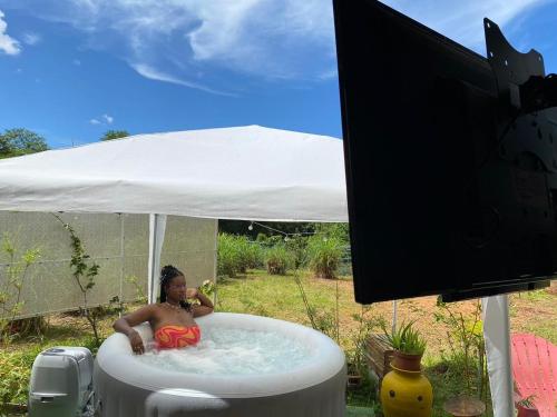 a boy sitting in a bath tub under a tent at Kaz'Jacuzzi, Jardin et parking privé - Matoury in Matoury
