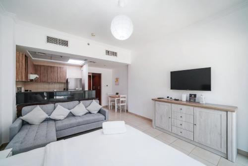 a living room with a couch and a flat screen tv at Studio close to Burj Khalifa and Downtown Dubai in Dubai