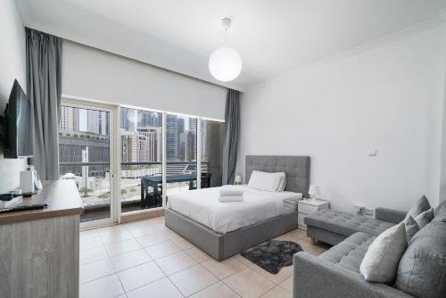a bedroom with a bed and a couch and a large window at Studio close to Burj Khalifa and Downtown Dubai in Dubai