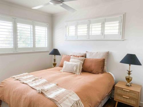 a bedroom with a bed with two lamps and two windows at Peregian House - beach front property in Peregian Beach