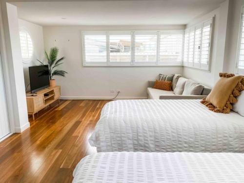 a white room with two beds and a couch at Peregian House - beach front property in Peregian Beach