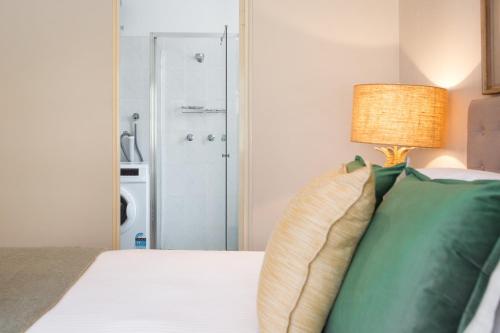 ein Schlafzimmer mit einem Bett mit grünen Kissen und einer Lampe in der Unterkunft Chic Apartment with Sun Lounge Near Manly Beach in Sydney