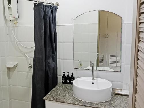 ein Badezimmer mit einem weißen Waschbecken und einem Spiegel in der Unterkunft Ampha Place Hotel in Mae Nam
